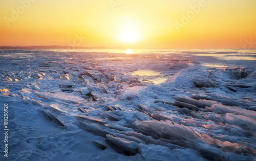 Winter landscape with frozen lake and sunset fiery sky.