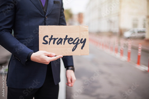 The concept of strategy. A young businessman in a business suit holds a sign in his hand.