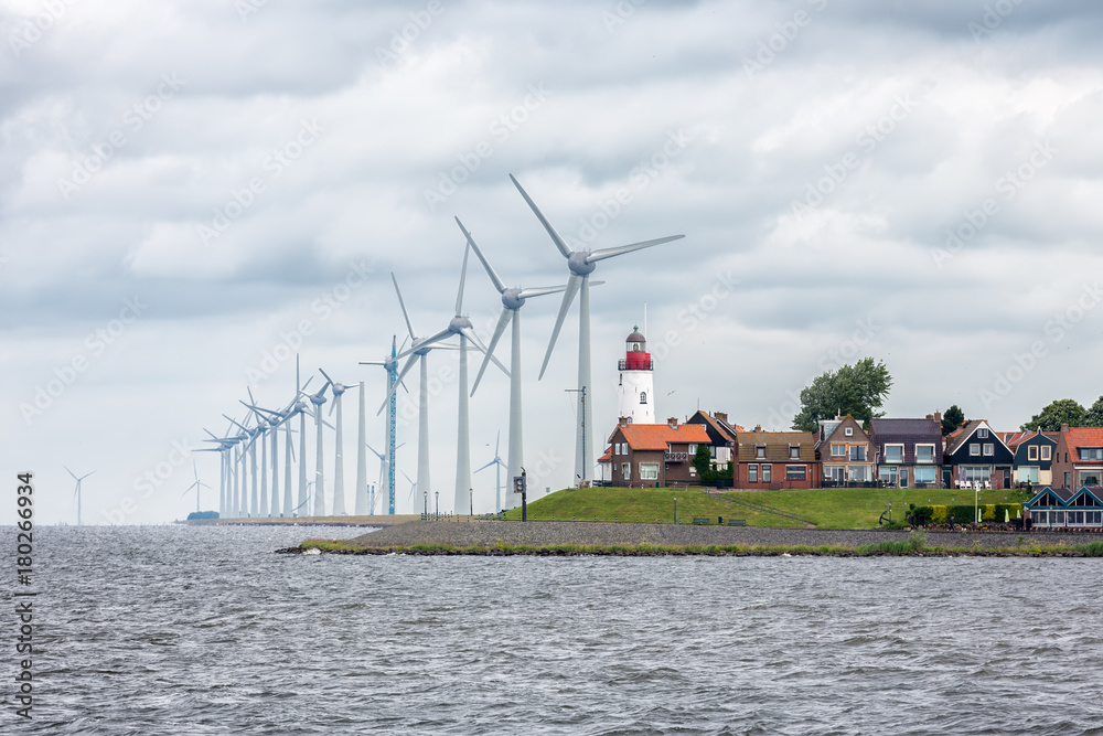 Seascape Dutch fishing village Urk with big wind turbines raising above the skyline of the houses - obrazy, fototapety, plakaty 