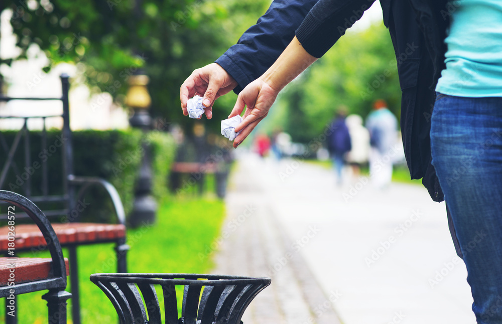Obraz premium guy and girl throwing paper debris into a street urn