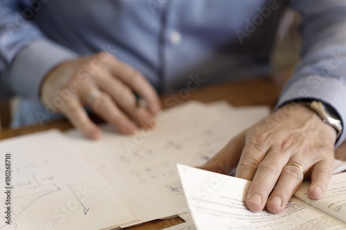 Hands of a businessman making calculations on a paper sheet. Soft background