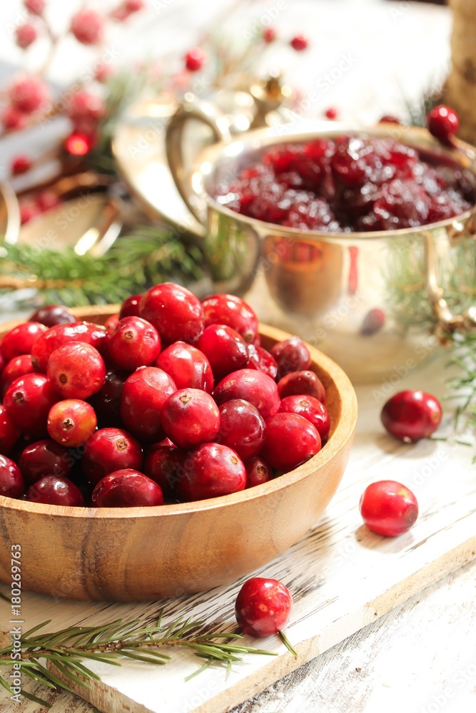Raw Cranberries served in a wooden bowl  on white wooden background, selective focus