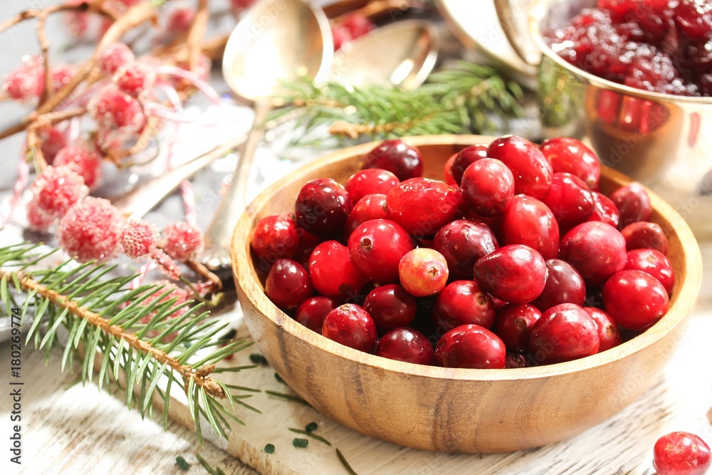 Raw Cranberries served in a wooden bowl on white wooden background, selective focus Raw Cranberries served in a wooden bowl on white wooden background, selective focus