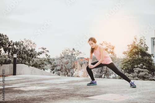 Asian woman stretching body in the evening,Exercise for good heathy,Female runner doing stretching exercise, preparing for evening workout in the park