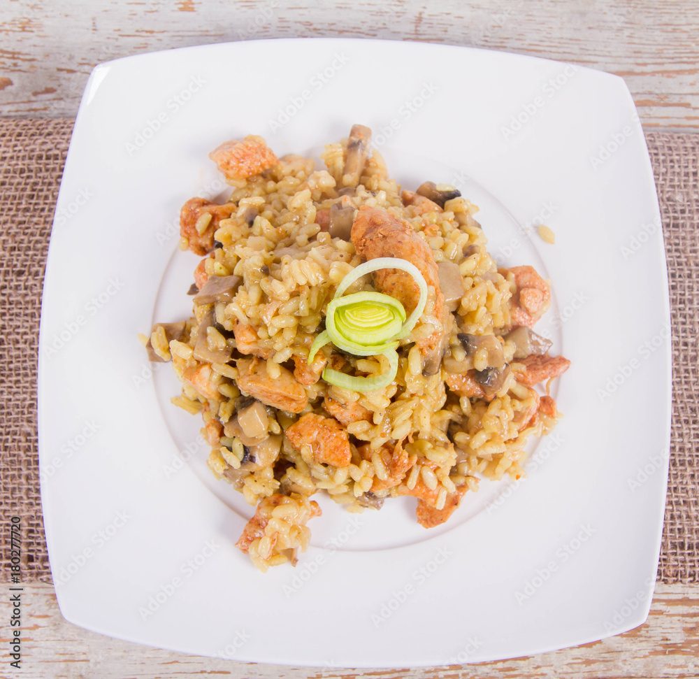 Risotto with mushrooms and chicken decorated with leek on a wooden background Risotto with mushrooms and chicken decorated with leek on a wooden background