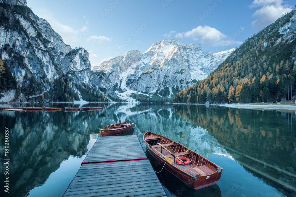 Naklejka premium Klarer Gebirgssee mit Booten und Steg vor felsiger Gebirgslandschaft 