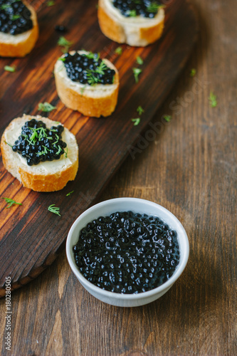 Fresh black caviar in a white ceramic bowl.