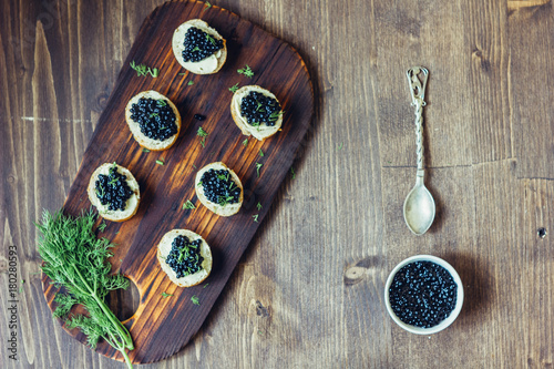 Top view of black caviar appetizers at wooden board. photo