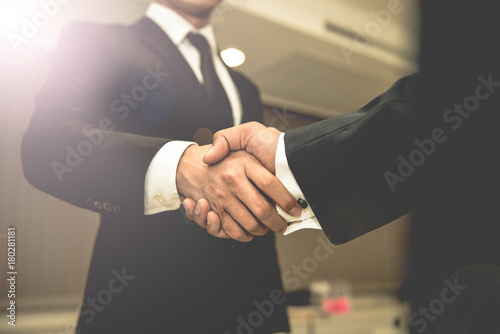 Asian Business people shaking hands, finishing up a meeting,mission complete,Two business people are holding hands to business cooperation in a future,len flare filter photo