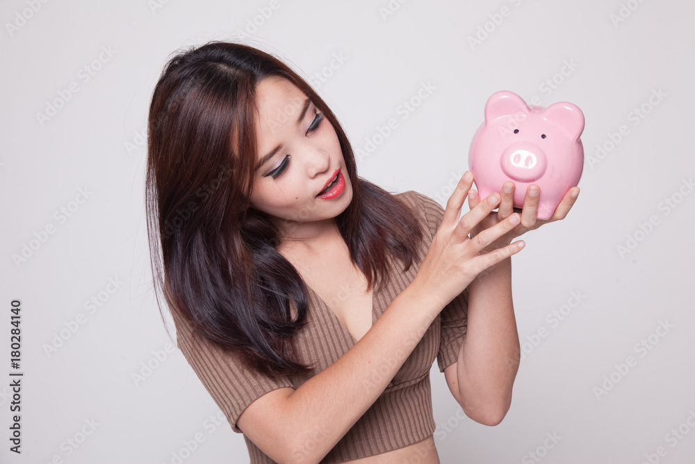 Young Asian woman with a pig coin bank. Young Asian woman with a pig coin bank.