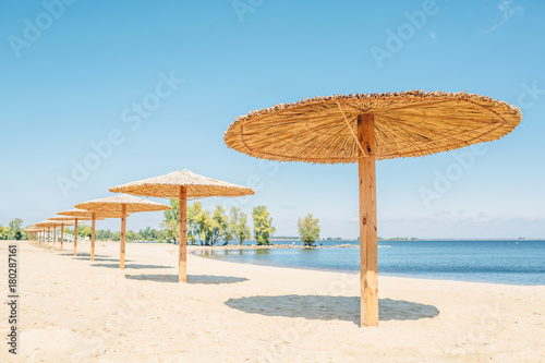 Fototapeta Naklejka Na Ścianę i Meble -  Sun shade bulrush umbrellas on the sand beach