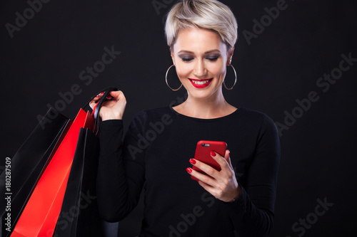 Black friday holiday. Happy blonde woman at shopping holding bags isolated on black background.. Copy space for sale.