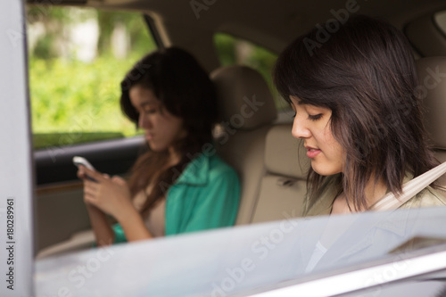 Teen girls texting in the back seat. © digitalskillet1