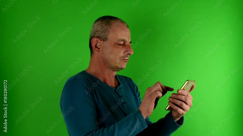 Mature mid aged man talking on a phone. Portrait of a mature white man texting in front of green screen. Mature mid aged man talking on a phone. Portrait of a mature white man texting in front of green screen.