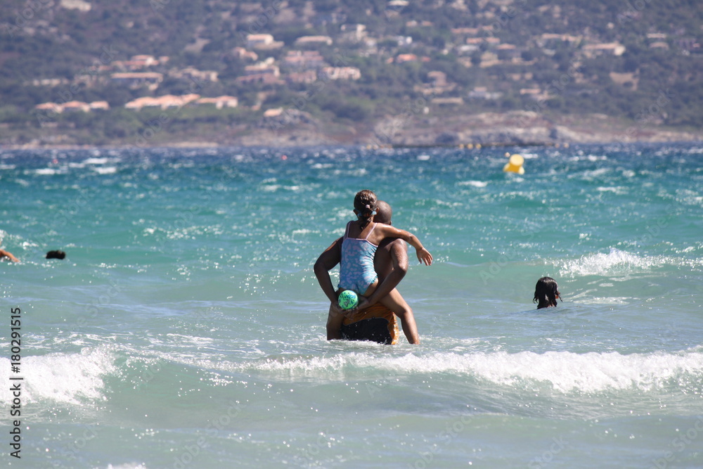 Corsica, Calvi. Family playing with the waves of the sea