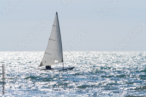 sailboat sails on a sparkling sea in a windy day