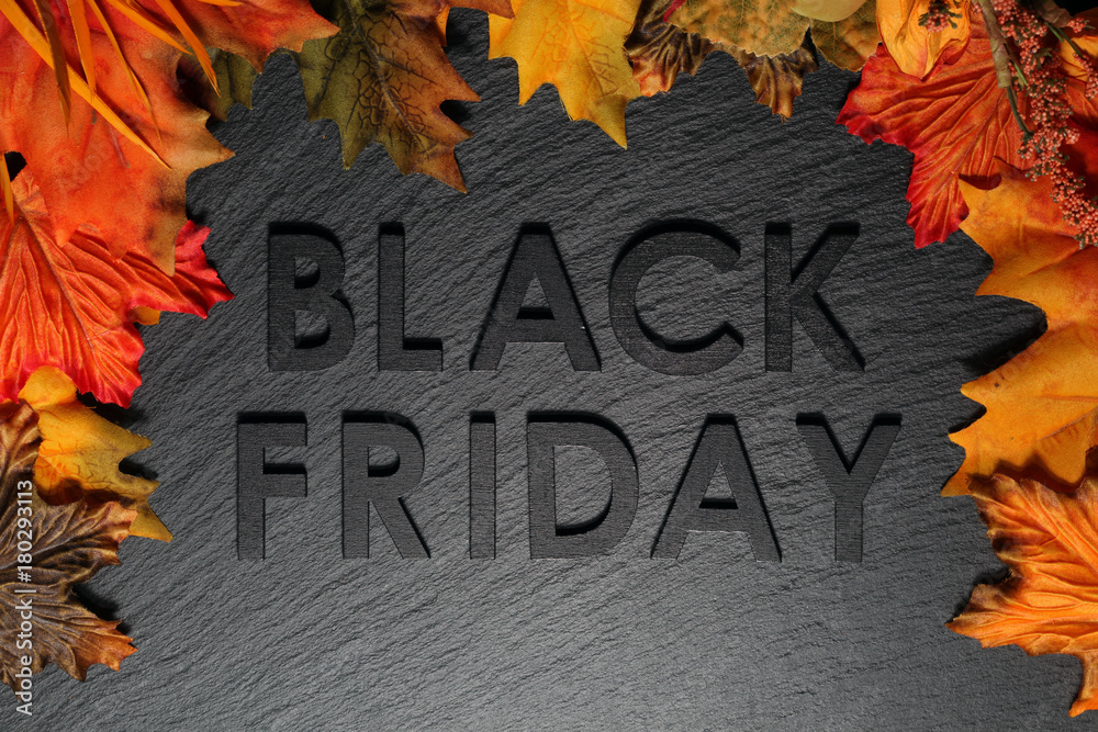 Black Friday text with autumn leaves on black slate background