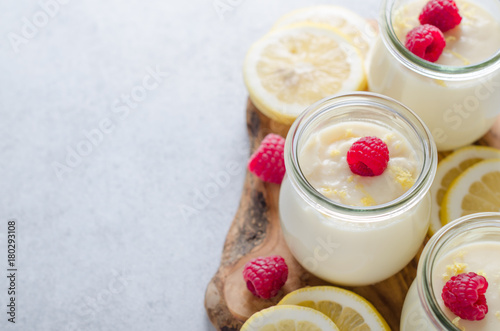 Fototapeta Lemon or vanilla curd in glass jars with raspberry and lemon sli