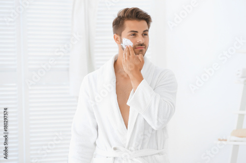 Young man applying facial c...