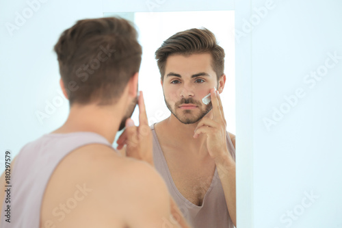 Young man applying facial c...