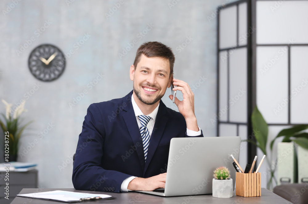 Handsome businessman talking on mobile phone while working in office