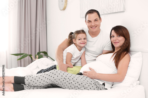 Happy young family on bed at home