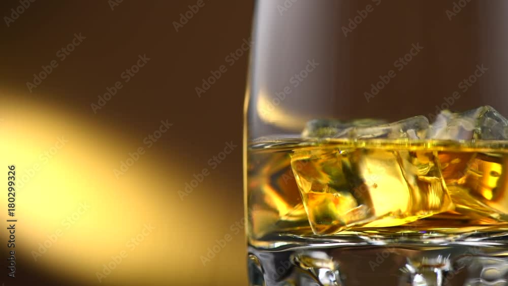 Whisky on the rocks. Glass of whiskey with ice. Rotation 360 degrees. 4K UHD video 3840x2160 Whisky on the rocks. Glass of whiskey with ice. Rotation 360 degrees. 4K UHD video 3840x2160