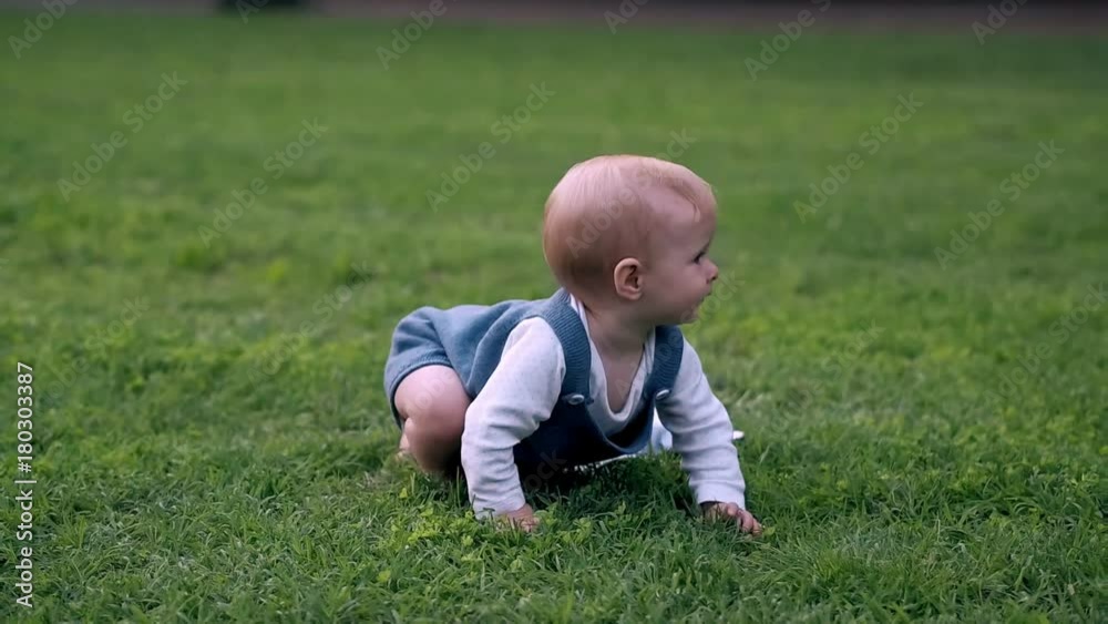 Baby girl crawling on grass on meadow. Little girl touching music headphones Baby girl crawling on grass on meadow. Little girl touching music headphones