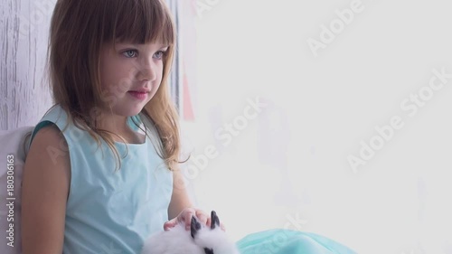 Pretty teen girl having fun, hugging and playing with decorative rabbit photo