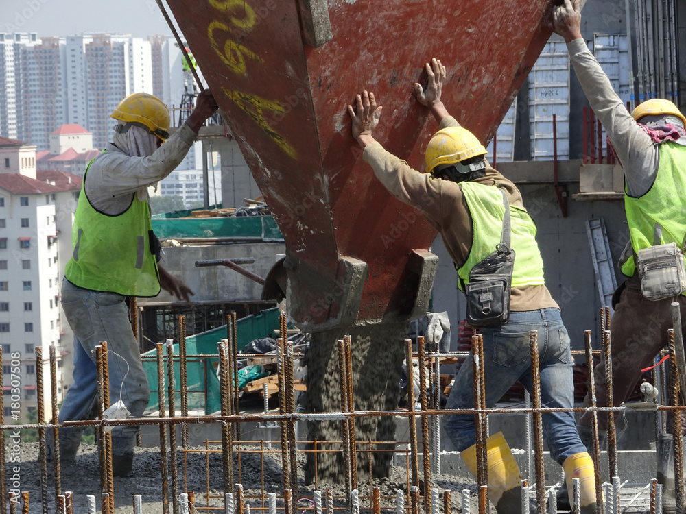 Group of construction workers pouring wet concrete using concrete