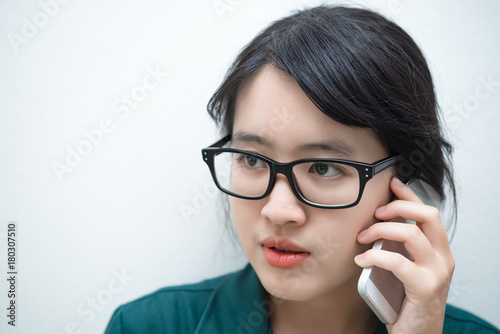 Closeup thai woman use smartphone on white wall,Asian girl call phone for work,Talking on moblie phone