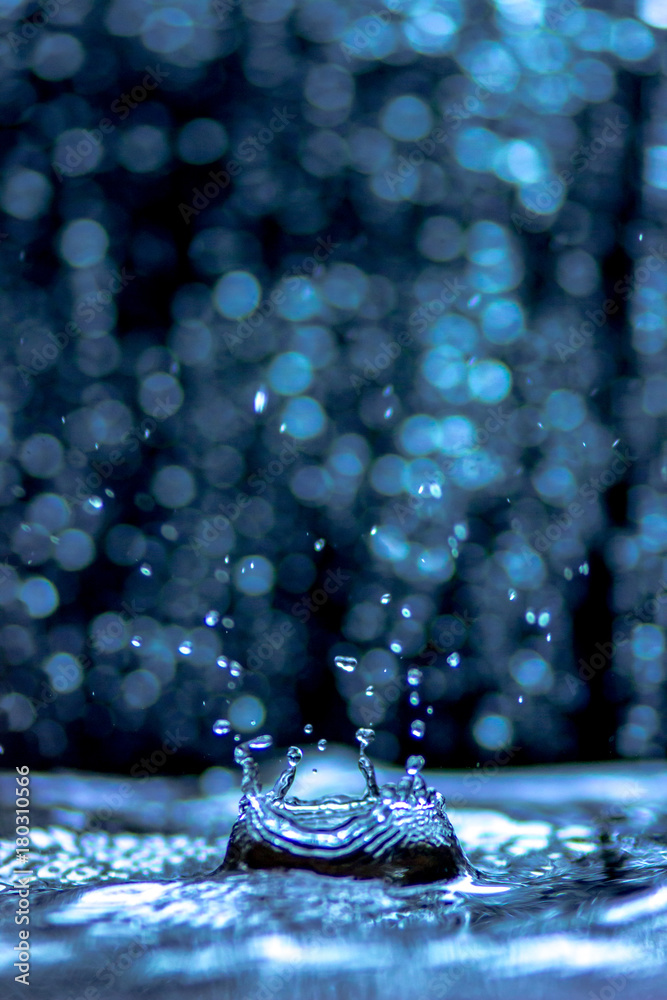 Water splash and wave, water drops and crown from falling into the water in light blue colors, on light Bokeh background