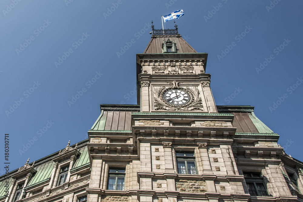 Classic clocktower building Quebec City Canada with flag of quebec on a sunny day blue sky