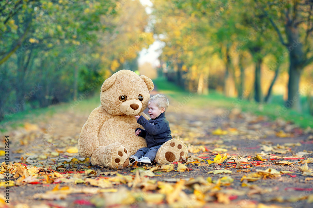 cute Little Boy and his teddy bear sitting together in autumn park Stock  Photo | Adobe Stock