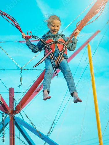 Girl tied by red seat belts goes up on the attraction.