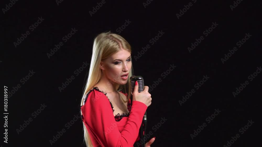 Girl sings songs for the clip. Black background. Side view Girl sings songs for the clip. Black background. Side view