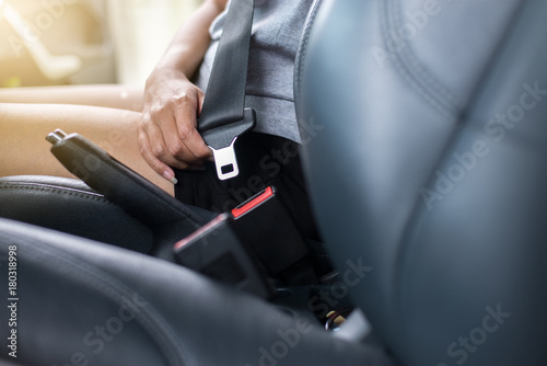 Close up of woman hands fastening or putting seat belt in car