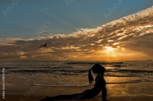 Fototapeta Naklejka Na Ścianę i Meble -  Silhouette of a person doing yoga with the sea in the background