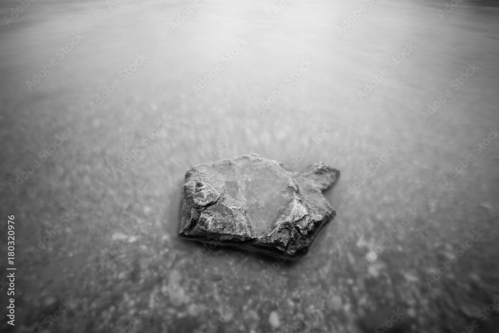 Rock in water lake long exposure