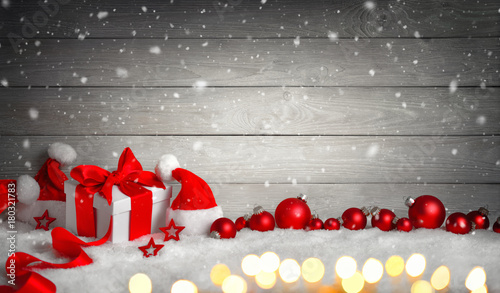 Weihnachten Hintergrund mit Holz, Geschenk, Weihnachtsmützen, Kugeln, Lichterkette und Schnee photo
