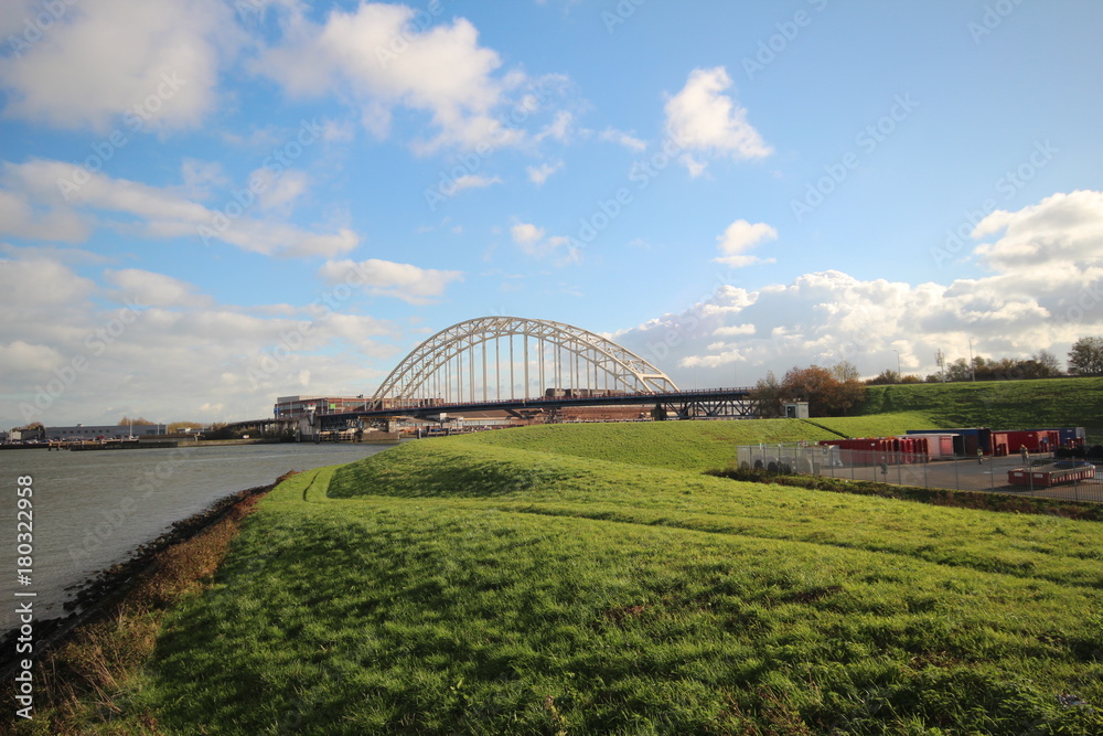 Bridge over river the Noord in the Netherlands with blue sky and big white clouds