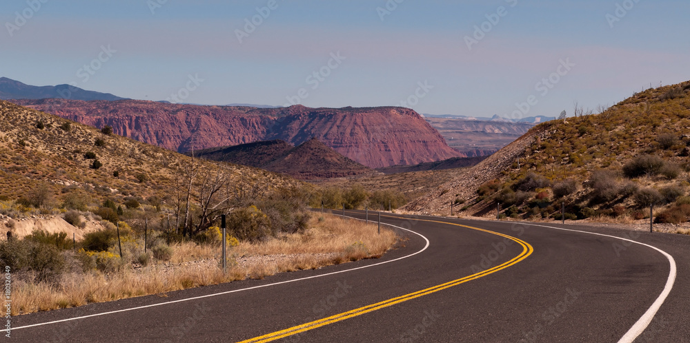 A winding road through Utah in the American southwest with a blue sky.