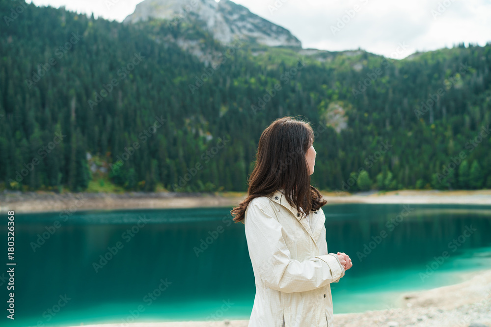 Young beautiful woman hiking in a national park, azure lake water and high mountain on the background.  Black Lake,  Montenegro