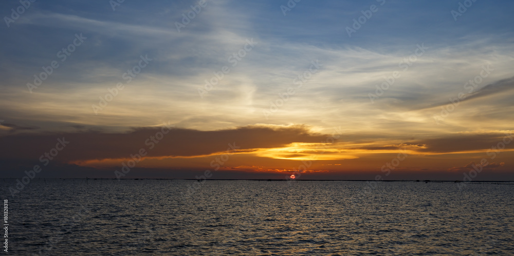 Orange sunset over sea shore and wetland with silhouette shell farm