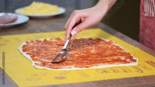 Putting tomato sauce on top of the pizza photo