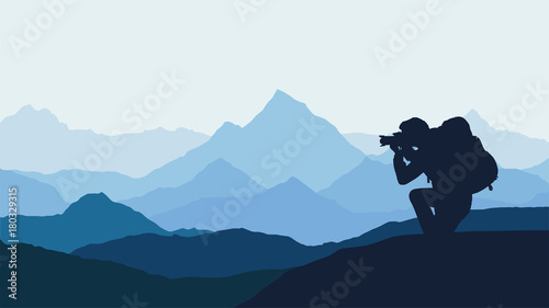 panoramic view of a mountain landscape with mist in a valley with a touring photographer under a blue sky