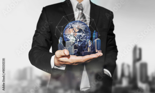 Businessman holding modern buildings with global network connection. Elements of this image are furnished by NASA