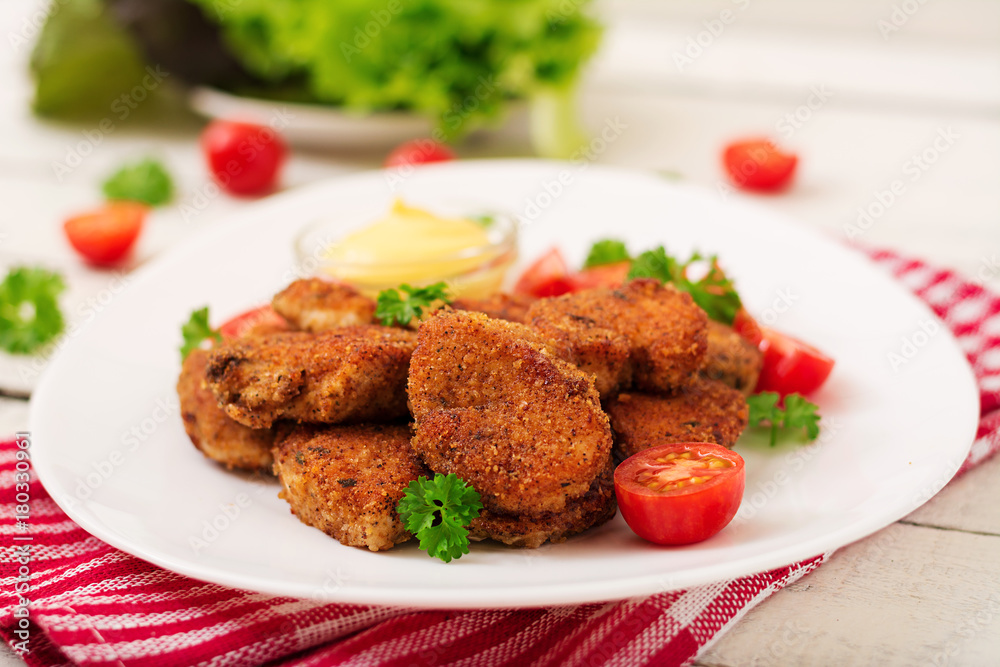 Chicken nuggets and sauce in plate on a white wooden background