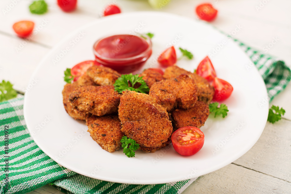 Chicken nuggets and sauce in plate on a white wooden background