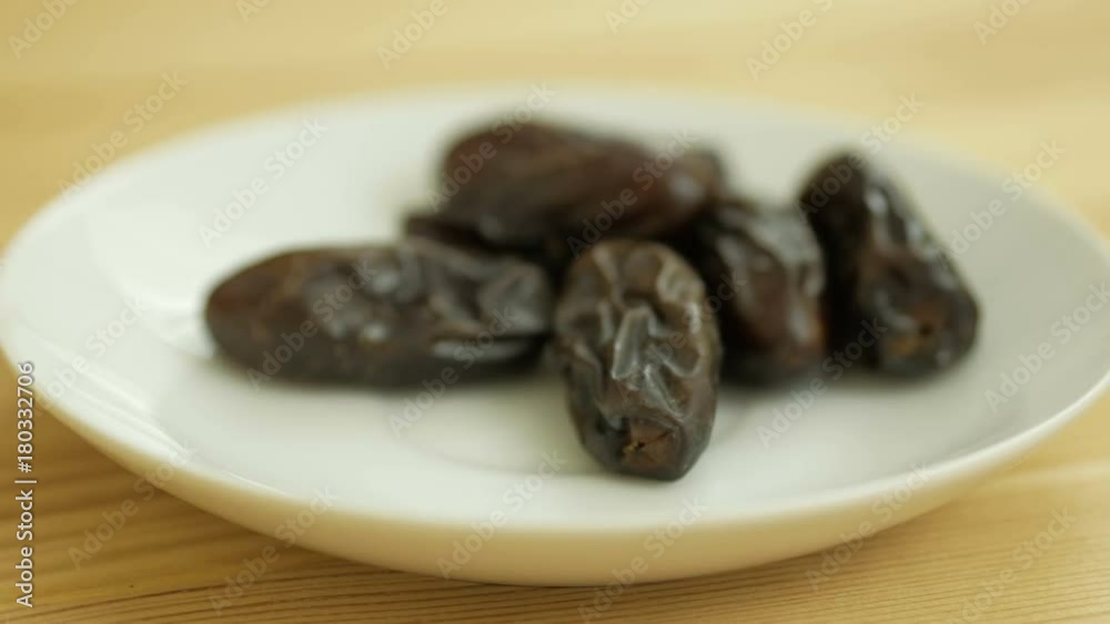 Hand taking dates fruit in the plate. People taking dates out of saucer. Hand taking dates fruit in the plate. People taking dates out of saucer.